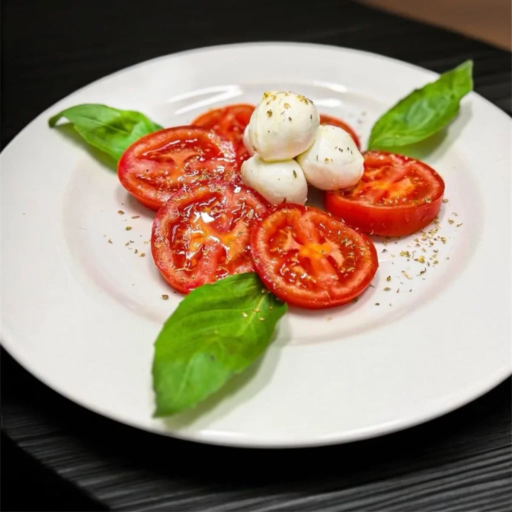 Pomodoro, mozzarella e basilico su un piatto bianco — VIBES